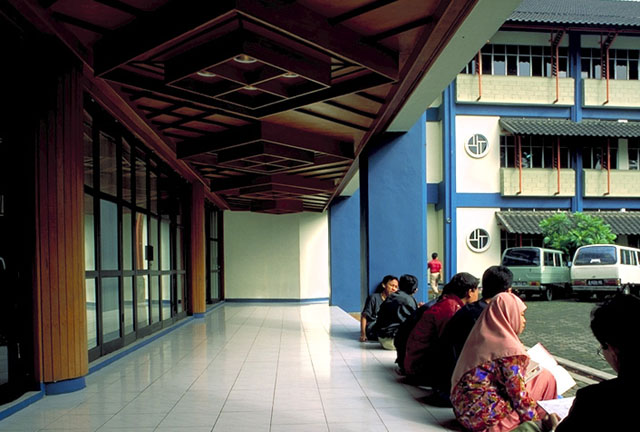 Students sit under the covered entry to the block 3 auditorium