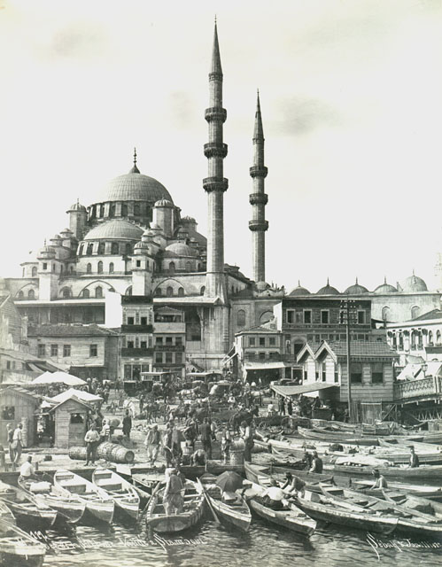 Yeni Camii Külliyesi - Exterior view from Golden Horn looking southwest, showing public square between the toll booths of the bridge (right) and the customshouse, with caiques lined up at the water's edge waiting for passengers to cross the channel