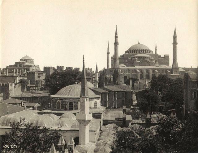 Elevated view from northwest showing the Hagia Sophia on the right and the Hagia Irene in the left background, separated by the fortified walls of the Topkapi Palace; the buildings of Haci Besir Aga Complex occupy the foreground.  The residential neighborhood surrounding the church was lost to urban planning interventions at the end of the nineteenth century
