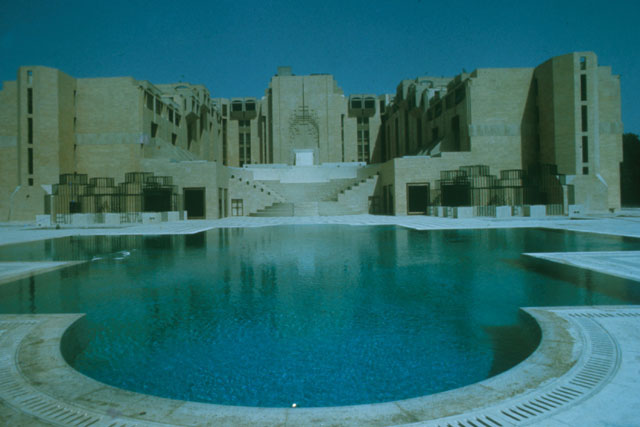 Exterior view across pool to monumental entrance with abstracted muqarnas design