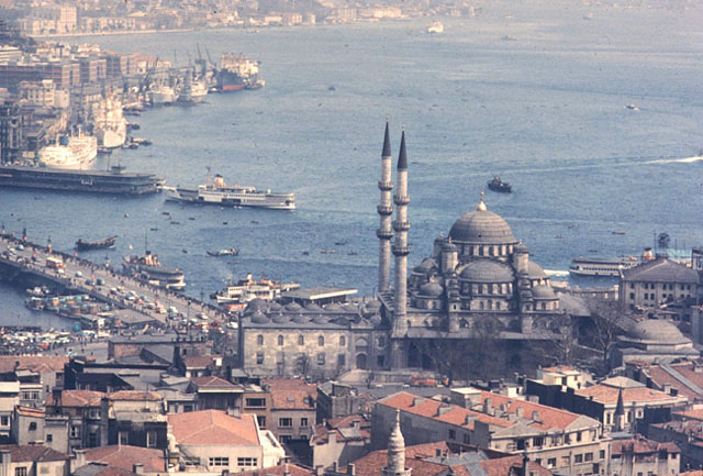 Elevated view from west-southwest showing mosque and tomb (right) with the Galata bridge, with the port of Karaköy seen at the mouth of the Golden Horn on the left. The Dolmabahçe Palace appears along the European shore of the Bosphorus in the upper left corner