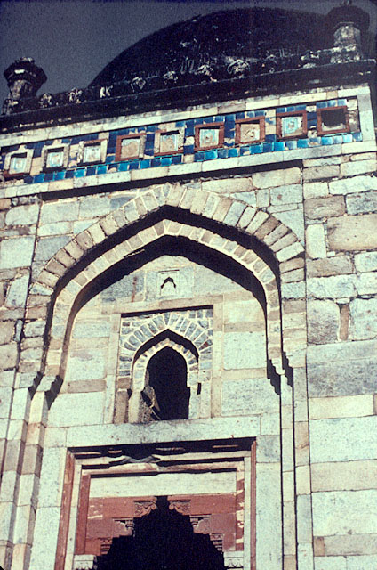 Exterior detail, showing arched frame of entryway and glazed tile decoration