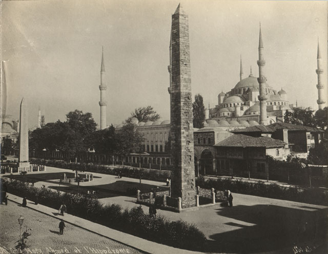West view of mosque shows western gatehouse of the precinct seen with the obelisks of the ancient Hippodrome in the foreground