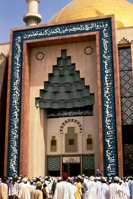 Exterior detail showing muqarnas decoration above entrance and calligraphy and tile work framing the door
