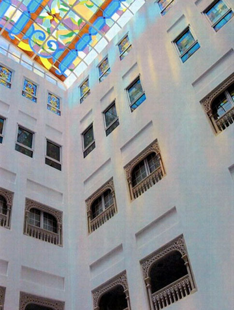 Interior view of atrium, looking up at colored glass ceiling