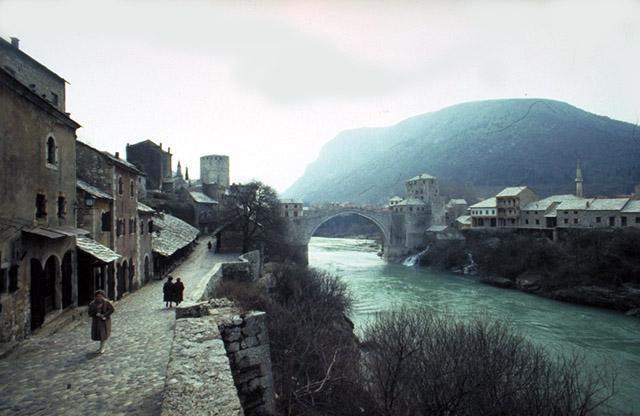 View of a walkway along the Neretva River with the bridge in the background