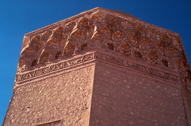 Exterior detail showing three-tiered muqarnas cornice and inscriptive band