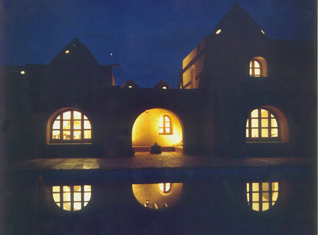 Exterior view showing front elevation reflected in pool at night