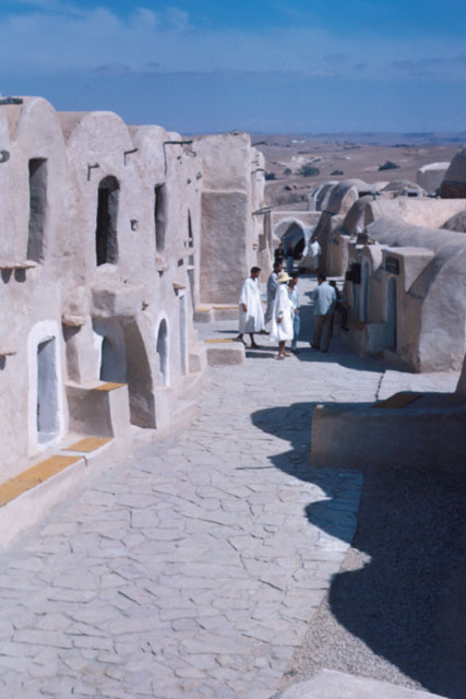 Exterior view along stone path through vaulted mud-brick buildings