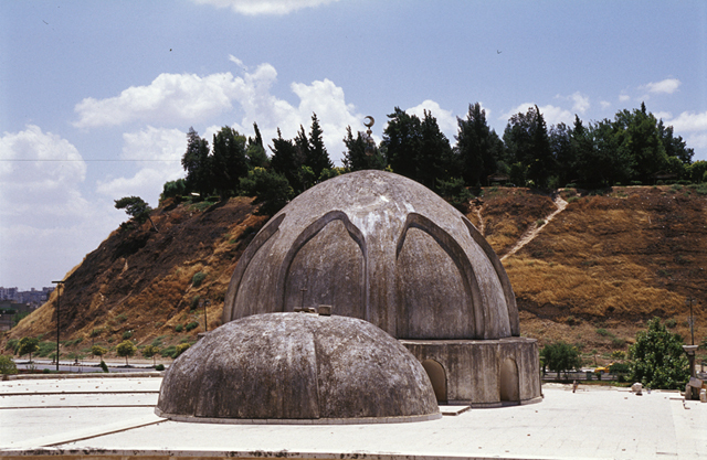 Roof view; prayer hall domes from south. A part of the Hama Citadel appears in the bacgkround, on the opposite side of the Orontes River