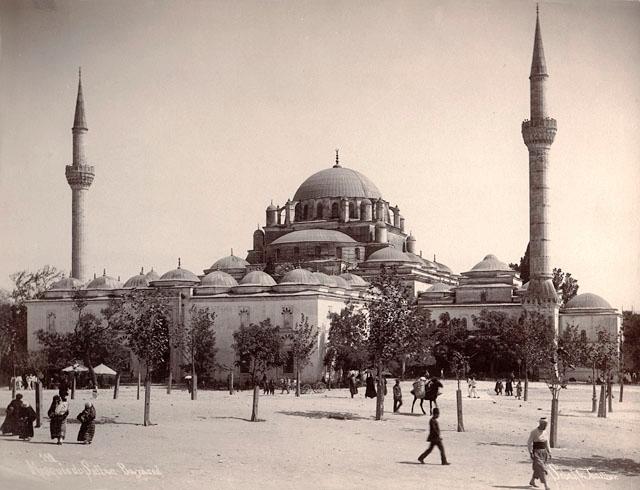 Exterior view of mosque from west, showing public square with newly planted trees in the foreground; the eighteenth century library annex is seen adjoining the minaret on the right