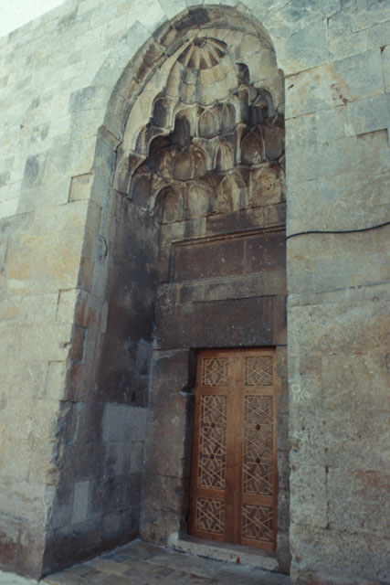 Exterior detail showing carved stone muqarnas above wooden entrance