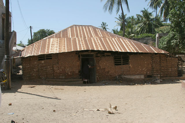 Exterior view of coral rag adobe structure with corrugated metal roof situated close to Riadha Mosque