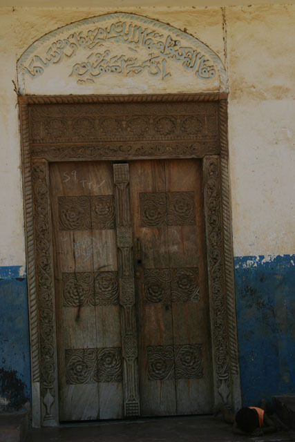 Exterior view of Swahili door in early classic rectangular design with foliated carvings and etched inscription above the header
