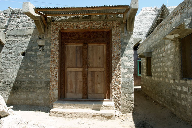 Exterior view of Swahili door in early classic rectangular design with corrugated metal overhang and coral rag door frame