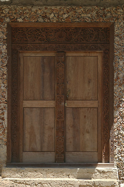 Detail view of Swahili door in early classic rectangular design with coral rag door frame and lotus leaf decorative carvings