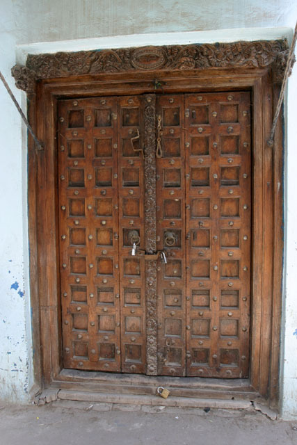 Exterior view of Swahili door in early classic rectangular design with brass studded detail, niched panels and decoratively carved center-post
