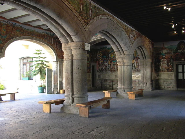 Exterior view of ground-level open space with low arches and wall paintings