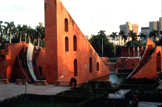 View of the Jantar Mantar complex from the northeast. The Samrat Yantra dominates in the foreground, while a part of the perforated curved wall of the Ram Yantra can be seen in the background. The plinth of the western hollowed sphere of the Jai Prakash Yantra is visible between the two instruments