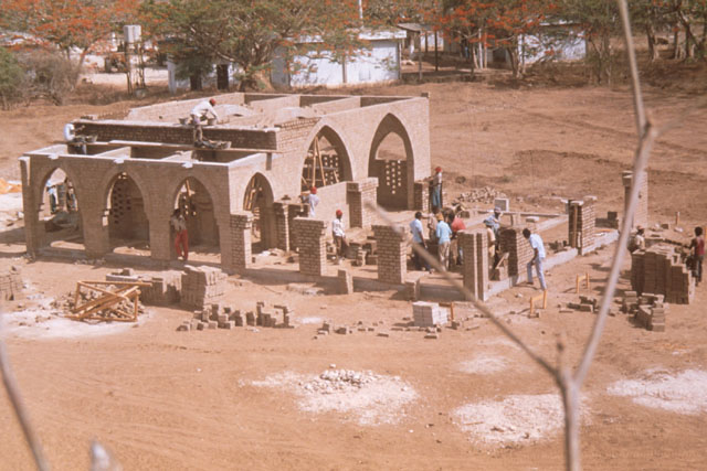 Elevated view showing building up of brick walls around arch and pillar structure