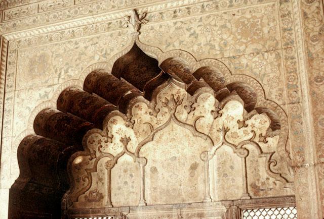 Interior detail showing floral carvings in tympanum of cusped arch and painted decoration on its spandrels