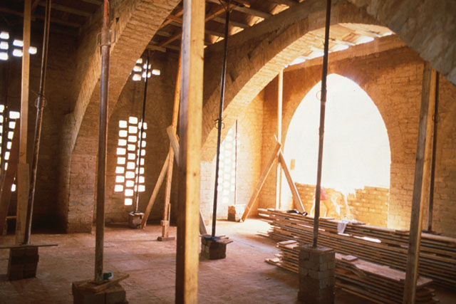 Interior view showing arched window frames and rectangular piers light sources in brick walls