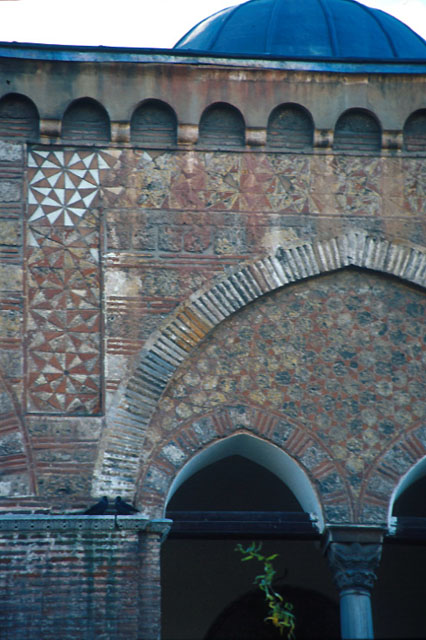 Exterior detail from upper part of northern façade; showing decorative brick scheme over arch of balcony and a Byzantine capital