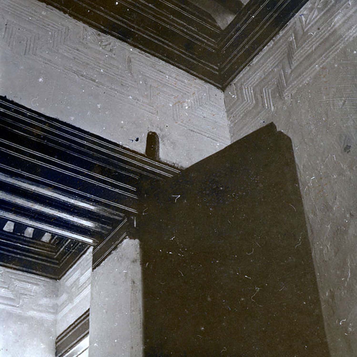 Detail view of upper part of front door on upper floor, showing top of door frame and wooden moulding detail
