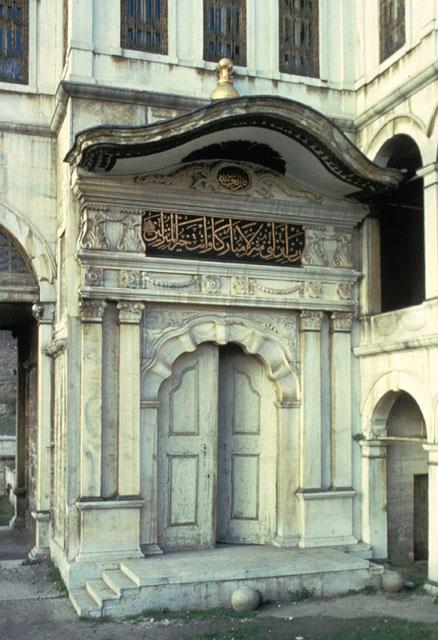 View of sultan's entryway into the royal lodge above; located adjoining the side arcade on the southwest façade, the arched entryway is flanked by ionic pillars and crowned by an inscriptive plaque under a wavy roof