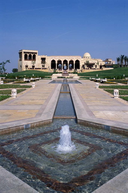 Exterior view from south, looking across landscaped lawn with water channel and pools