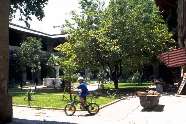 <p>View of a courtyard with a boy on a bicycle in the ofreground.</p>
