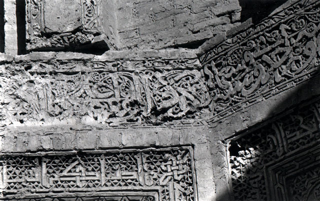 Interior view with detail of carved stucco naskhi and kufic epigraphic frieze above blind arches