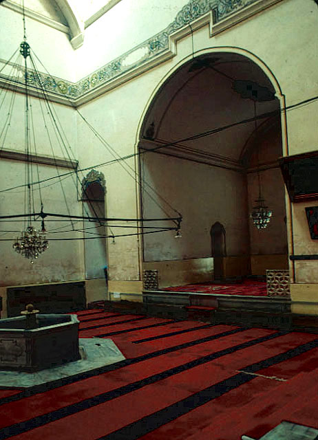A view of the main court of the mosque, looking towards the northern wall and the eastern eyvan and the fountain in the center of the space; the door to the left of the eyvan opens to a smaller room