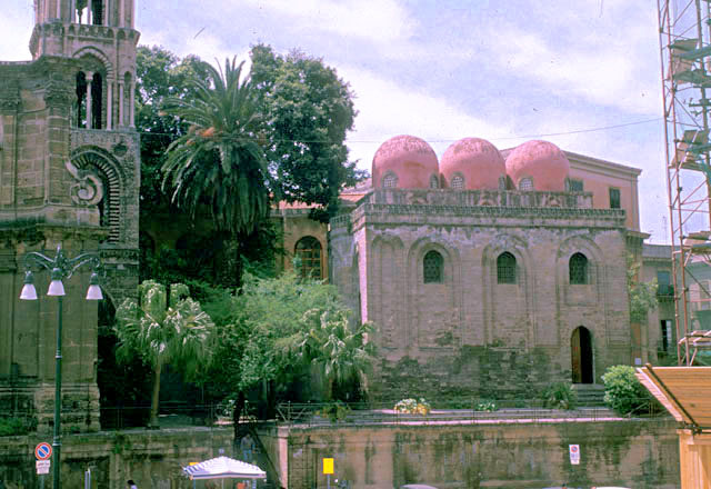 Exterior view showing three domes of the nave and side portal. Church of Santa Maria dell'Ammiraglio appears on the left