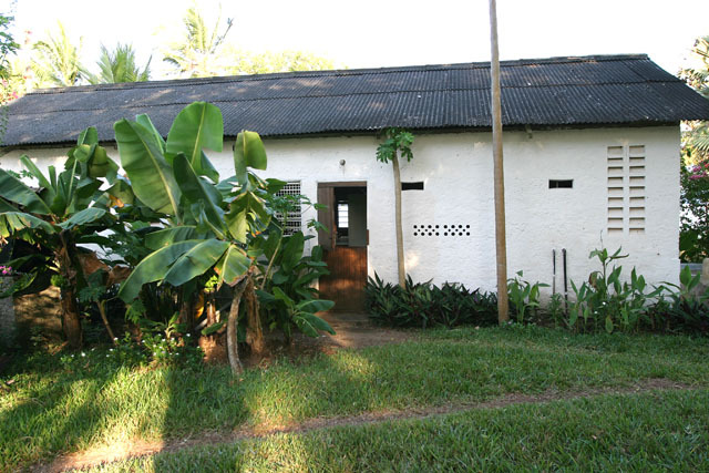 Exterior view of cottage with corrugated metal roof and decorative ventilation slits on wall