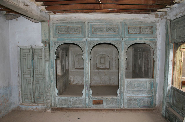Internal decorated timber partition in south winter room with carved plasterwork behind, prior to conservation