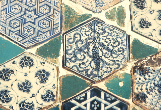 Interior detail from the prayer hall; hexagonal tiles with varied designs in white and blue, interlocked with triangular turquoise pieces in between forming a star pattern