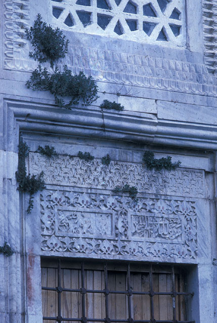 Exterior detail showing carved arabesques over a lower window along the qibla wall