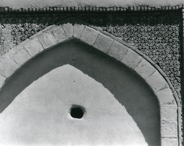 Detail from northwest wing of courtyard, showing upper part of arch at left with decorative brickwork in spandrels