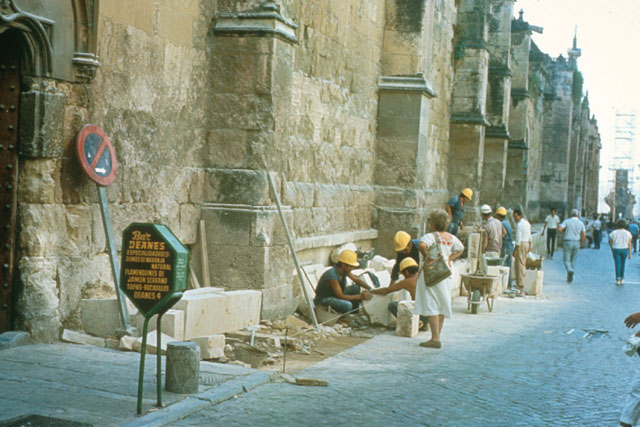 Exterior view showing stone masons working on wall