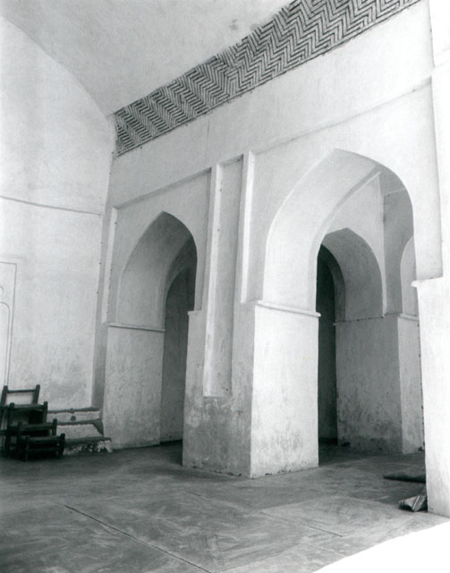 Interior view of sanctuary iwan showing west corner, with the edge of mihrab and wooden minbar seen at left