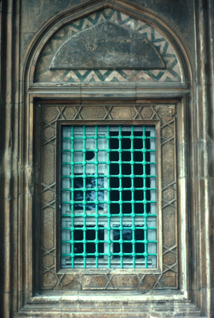 Exterior detail of a window, surrounded by a marble frame of inscriptions and crowned with ogee tympana