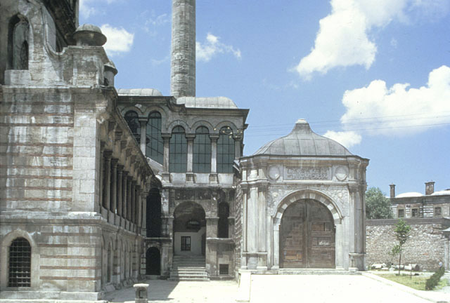 Exterior view from southeast, looking down the northeast arcade towards the arched side entrance with stairs leading into the mosque. Above the the entrance is the corridor leading into the sultan's lodge; it is accessed through a ramp with a monumental stone gate, seen on the right