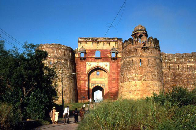 Exterior frontal view of Bada Darwaza with two large bastion towers flanking the arch. One has a chatthri missing.
