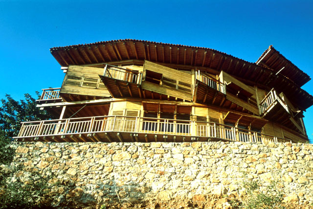 Exterior view showing timber construction balanced on a stone plinth