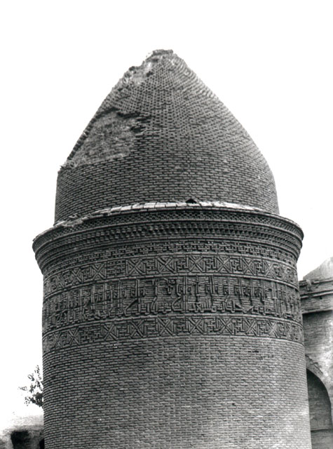 Exterior view showing upper portion of tower with brickwork epigraphic band