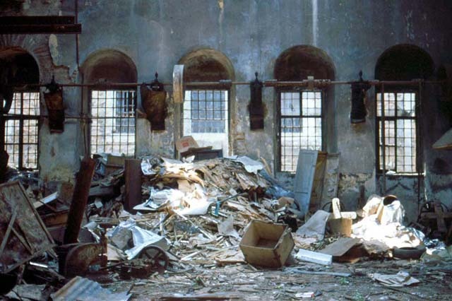 Interior view of mint workshop filled with garbage, before restoration