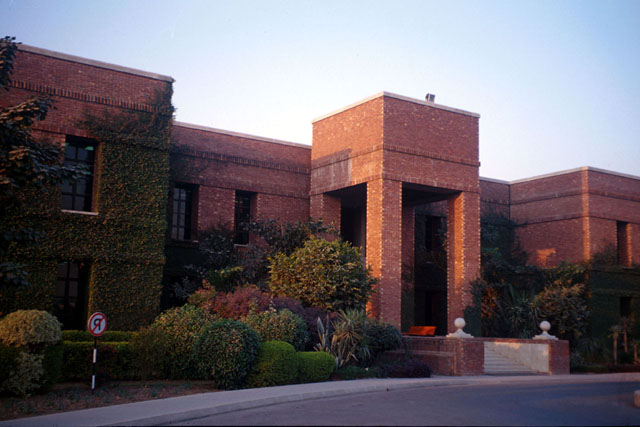 Exterior view showing stark rectilinear brick form with lush plantings