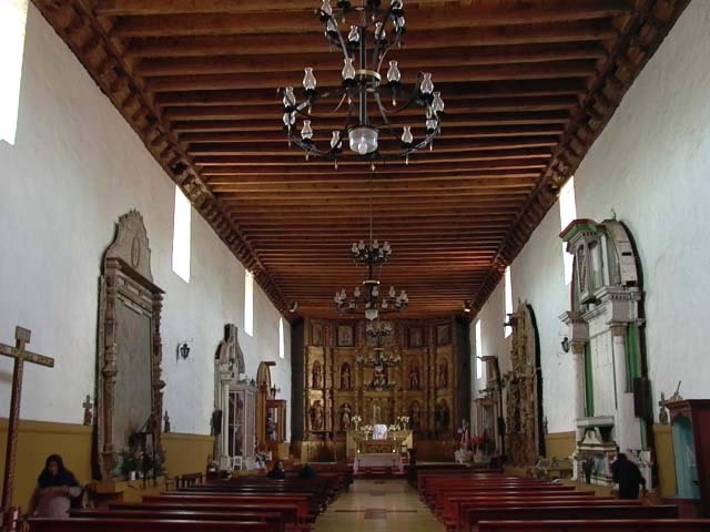Interior view towards the altar, showing wooden ceiling and pews