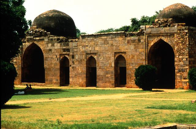 Exterior view of vaulted buildings and domes in the background